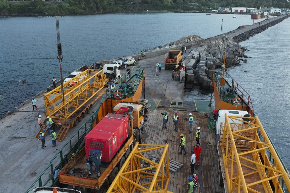 Boingoma Port breakwater and quay construction with workers, crane sections, trucks and a marine transport vessel