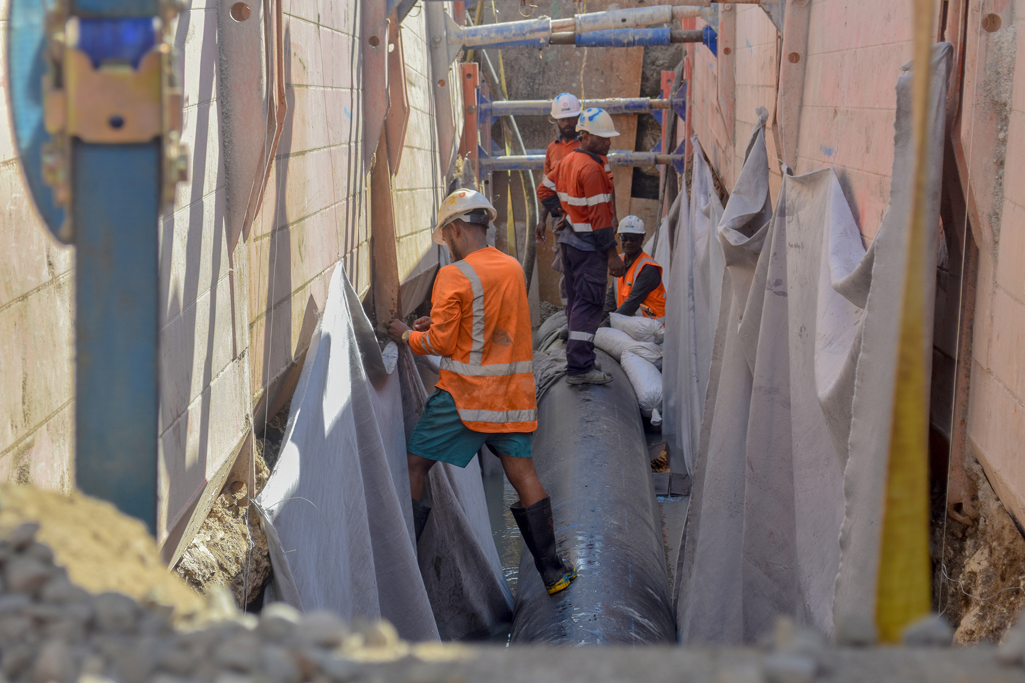 Workers install a large-diameter sewer pipe inside a sheet-piled trench on the Fisheries-to-Ranadi section in Honiara in 2024