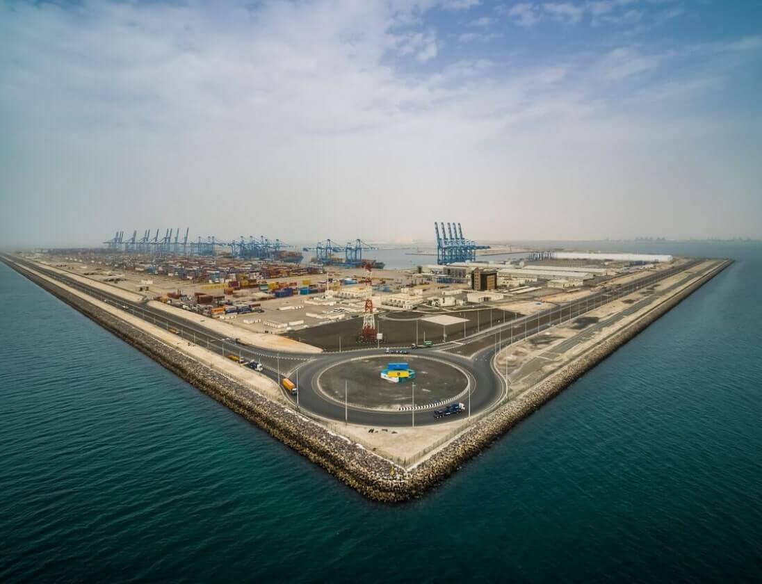 Aerial view of AD Ports Group port infrastructure with breakwaters, terminal yards, quay cranes, and waterfront access