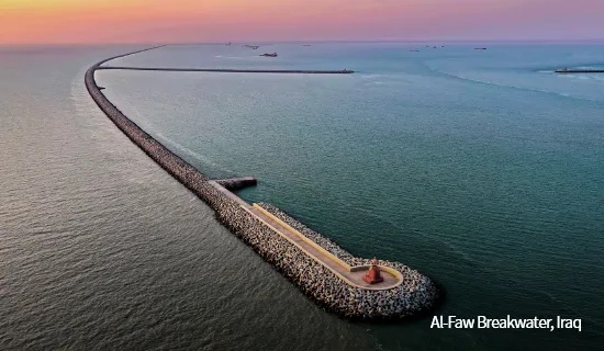 Aerial view of Daewoo E&C's curved rock breakwater at Al-Faw extending into the sea at sunset