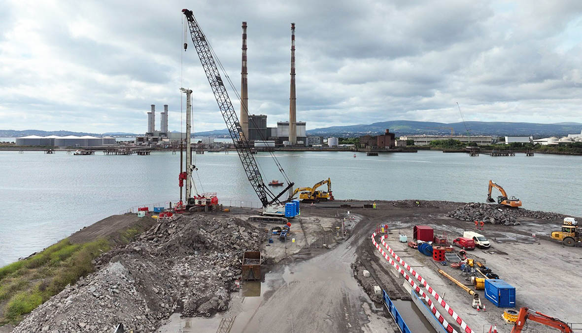 Aerial view of marine piling and earthworks at Dublin Port's MP2 Berths 52 and 53 site with Poolbeg chimneys across the River Liffey