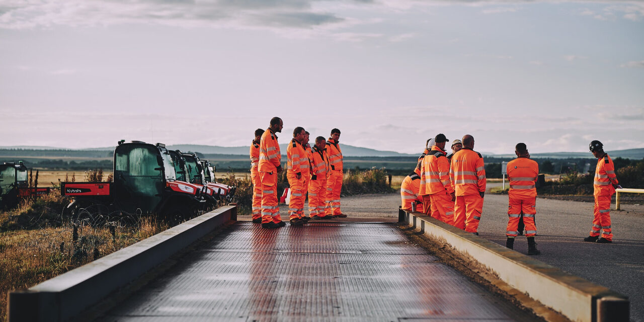 Haventus site personnel in orange safety clothing gathered beside an industrial platform and site equipment