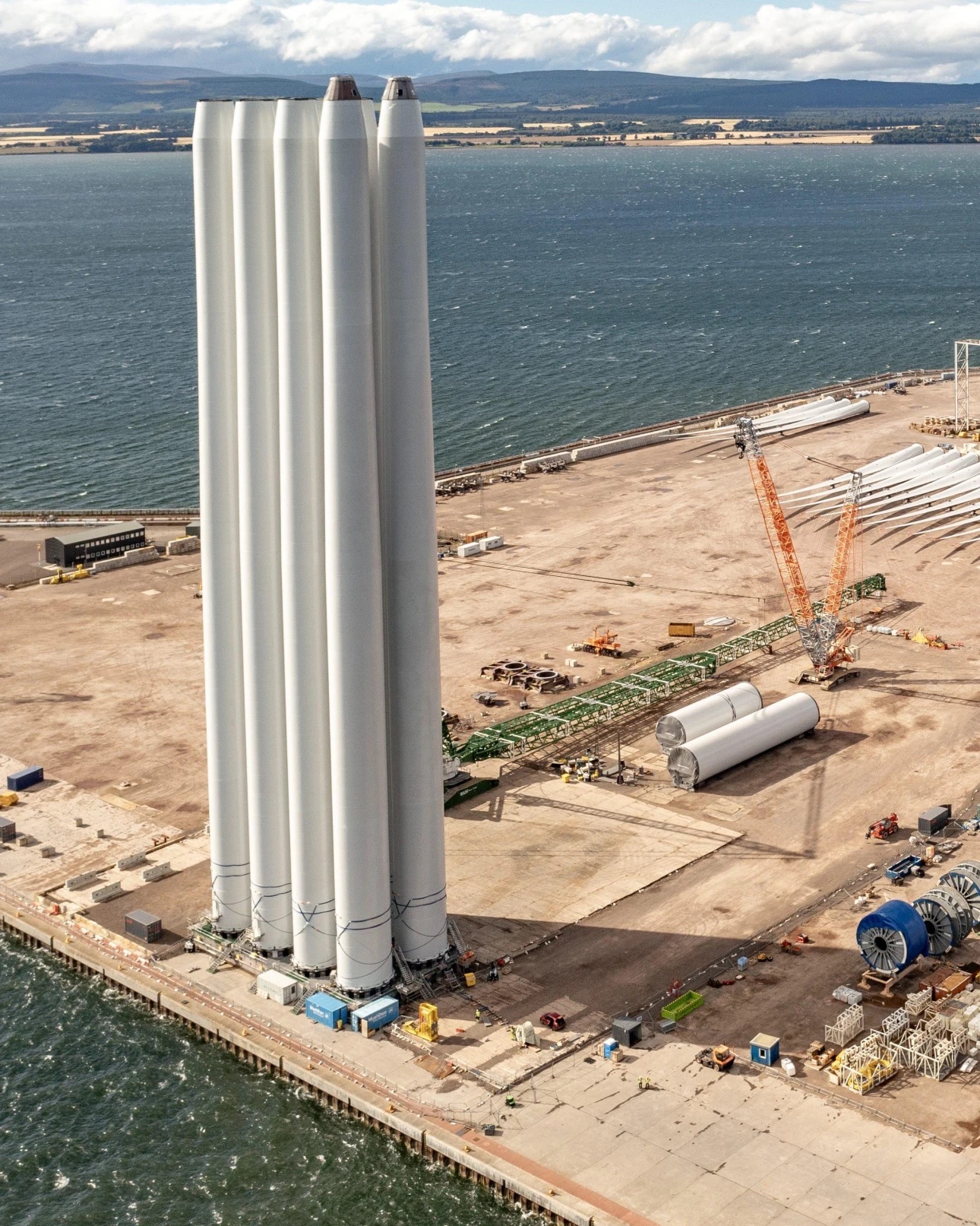 Wind turbine towers and nacelles being marshalled beside a heavy-load quay at Port of Nigg