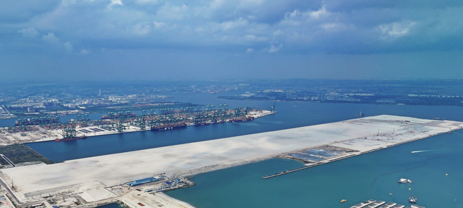 Aerial view of Tuas Port showing operating container berths, reclaimed land, marine work areas, the port basin and working craft