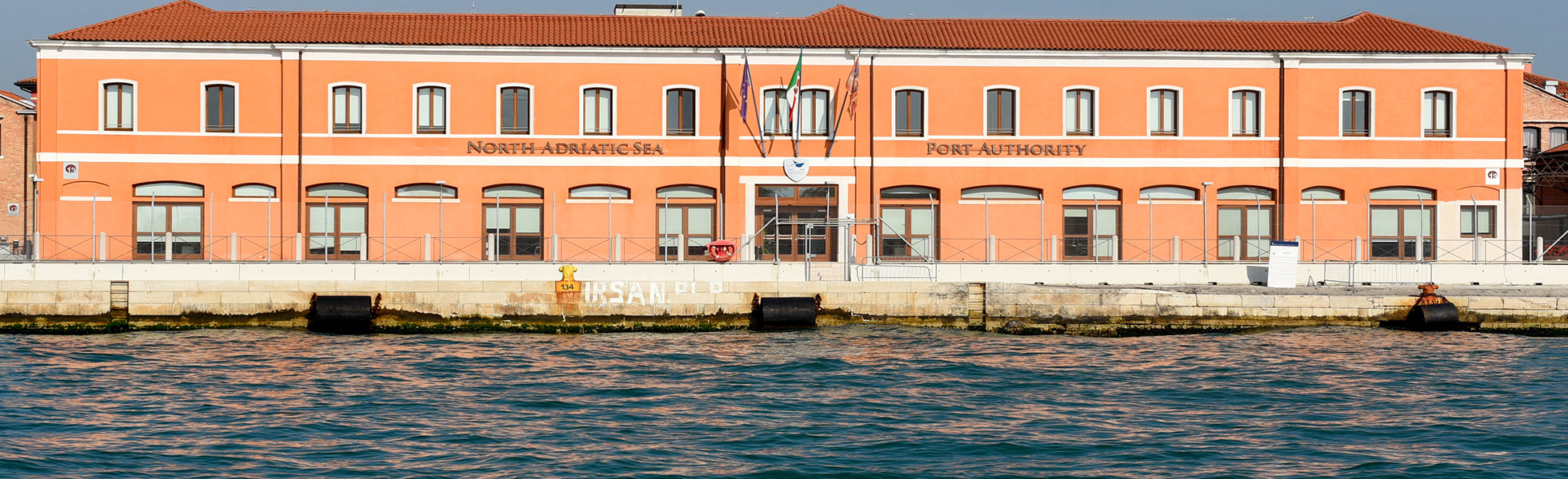 North Adriatic Sea Port Authority's Santa Marta headquarters on the Venice waterfront, with the authority name, flags and quay edge visible