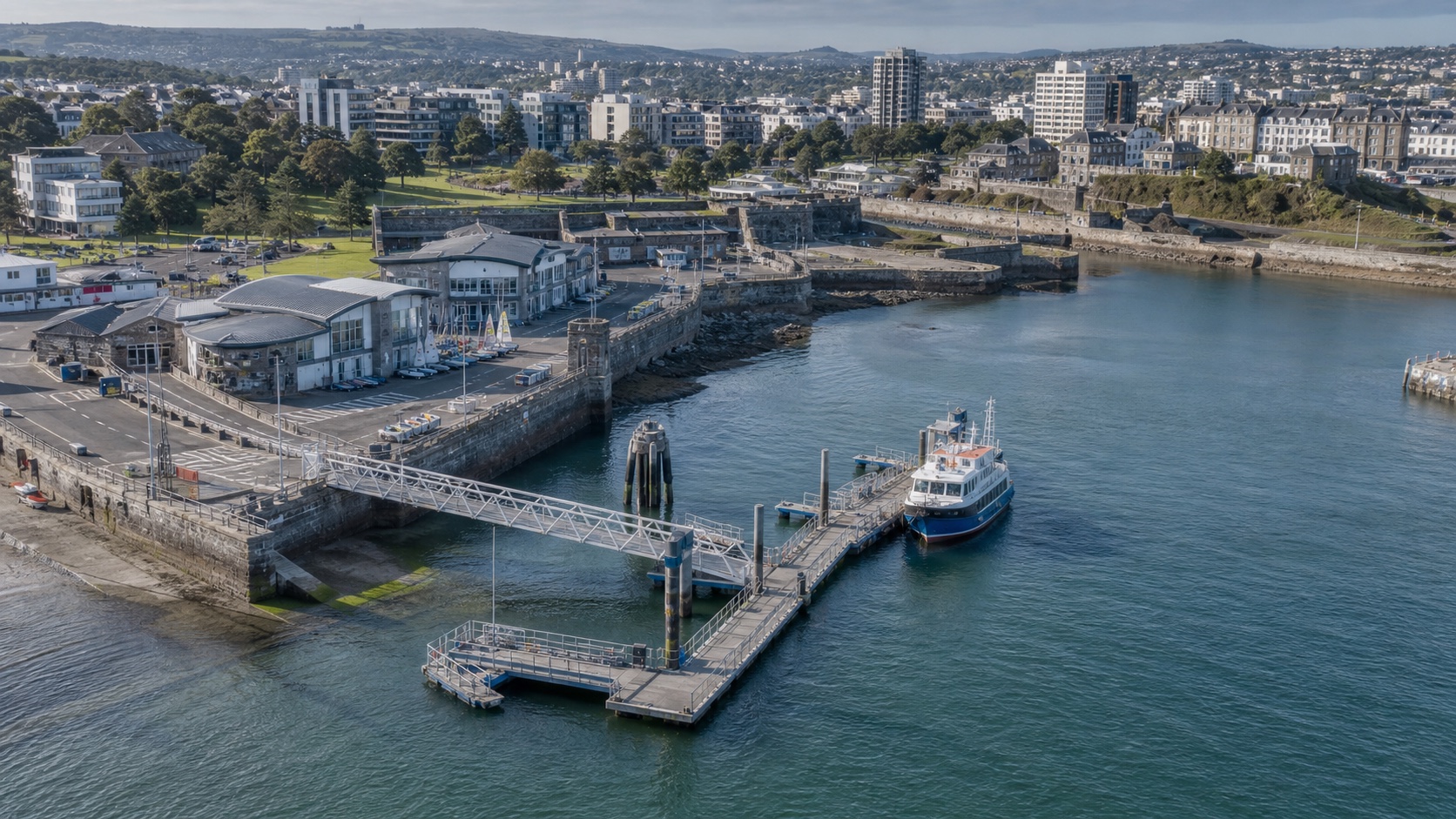 Aerial visualization of a Plymouth-like waterfront with a public ferry pontoon, accessible bridgehead, seawall, slipway and watersports centre