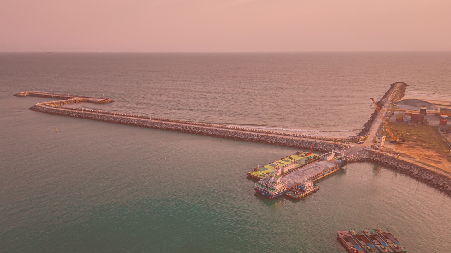 Aerial view across the Port of Cotonou entrance, breakwaters, harbour basin, working vessels and marine construction area
