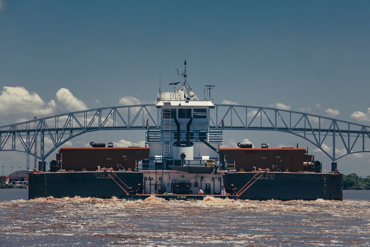 Commercial tow and barges navigating the Sabine-Neches Waterway beneath an industrial bridge