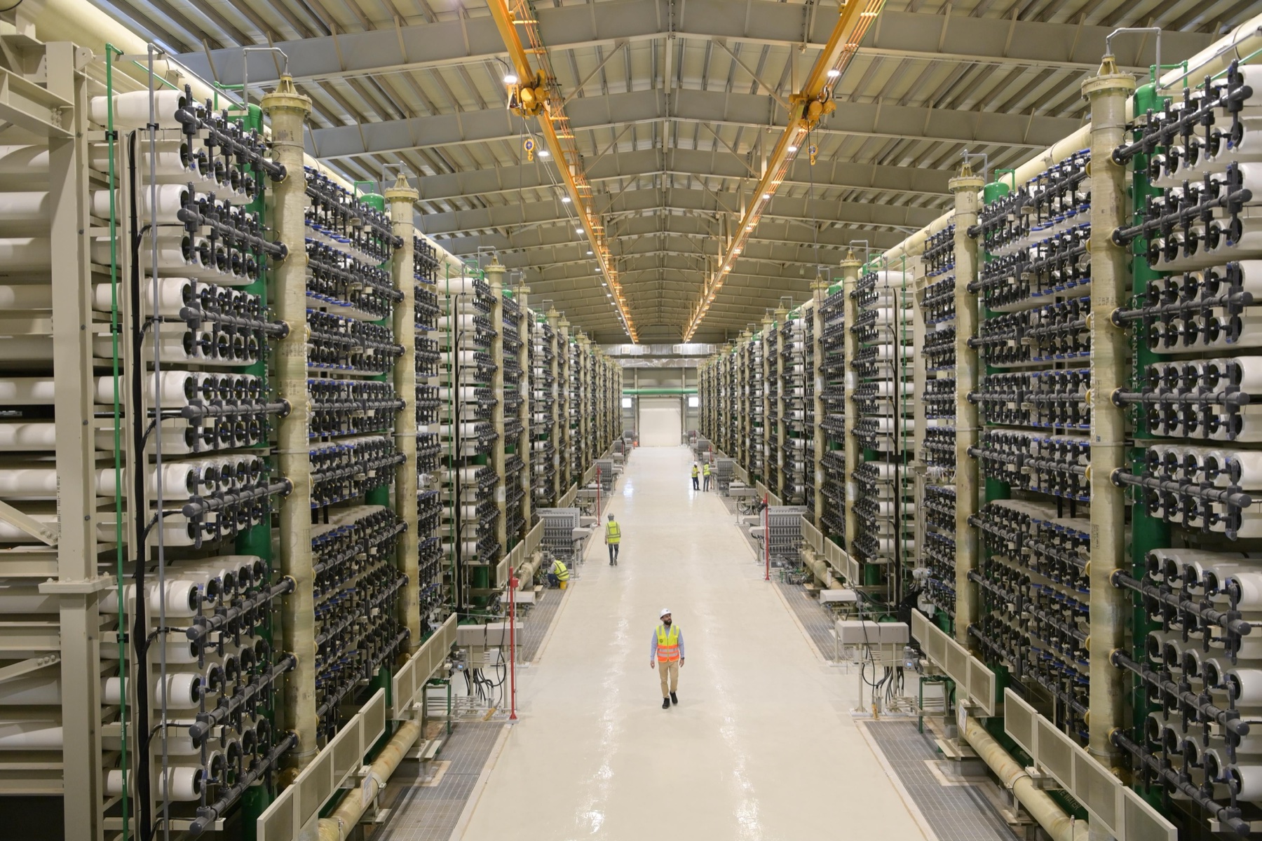 Rows of reverse-osmosis membrane pressure vessels and blue pipework inside a Saudi desalination facility