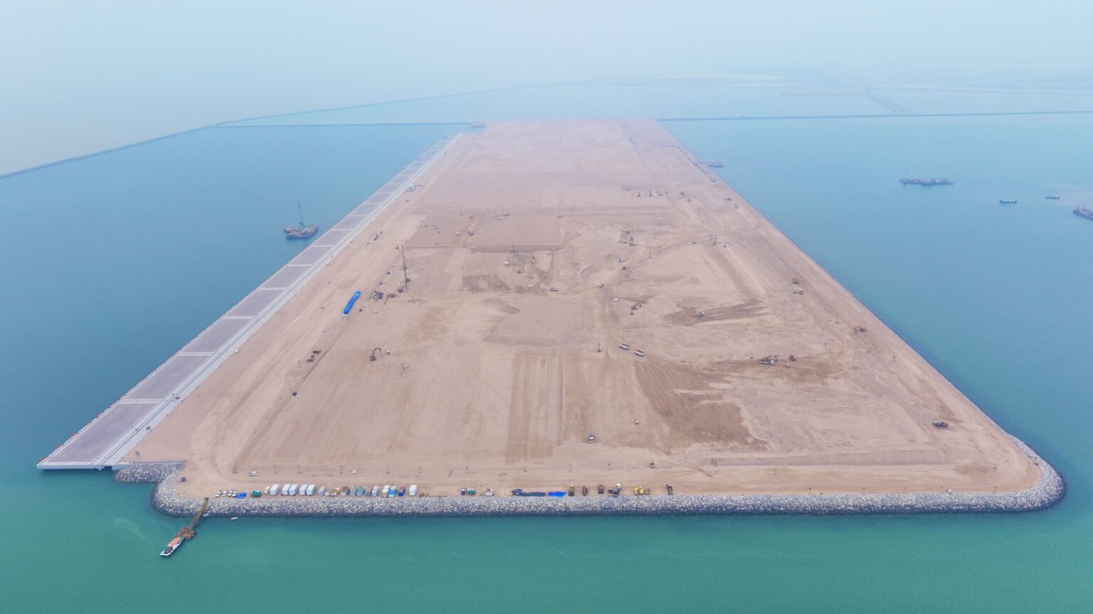 Aerial view of reclaimed terminal land, quay construction, and offshore breakwater works at Al Faw Grand Port in Iraq